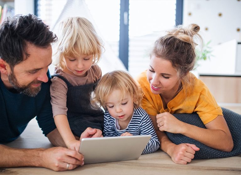 A family looking at a tablet while sitting on the floor.