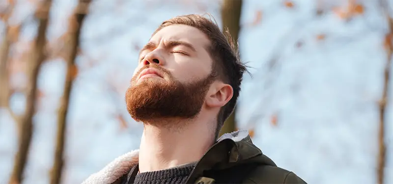 A man stands outside with his eyes closed, gently tuning into his body to notice early signs of emotional shutdown.