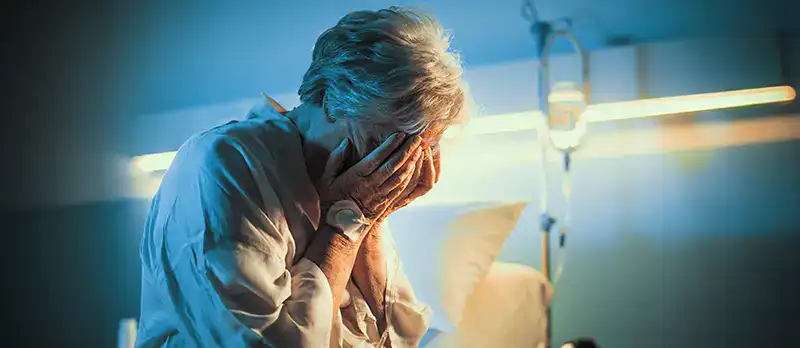 Trauma Solutions: A pen, paperwork, and two wedding rings on a table with a man and woman sitting in the background, both appearing serious with arms crossed.
